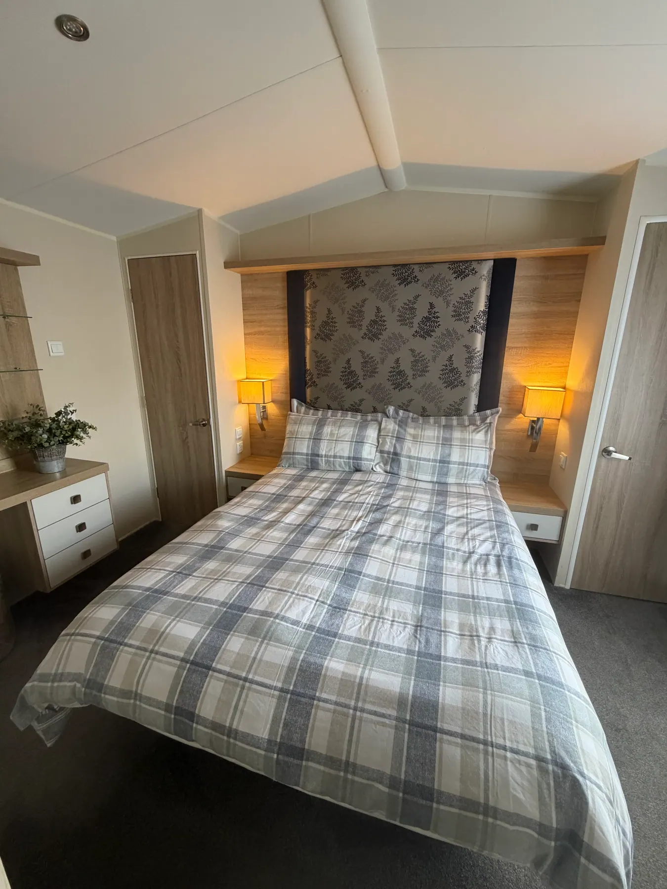 King-size bedroom inside Tern 32 with blue-and-white plaid bedding, patterned headboard panel and bedside lamps