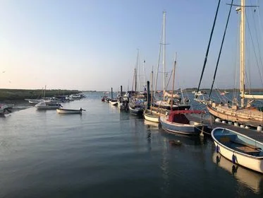 Wells harbour at dusk with boats, the quay and warm lights reflected in the water