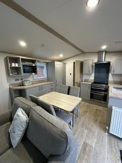 The kitchen and dining area inside Windsor 30 with grey units, a dining table, range-style oven and wood-effect floor