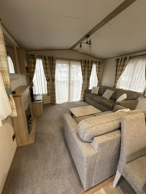 The lounge inside Windsor 30 with grey seating, patterned cushions, a wooden coffee table and checked curtains